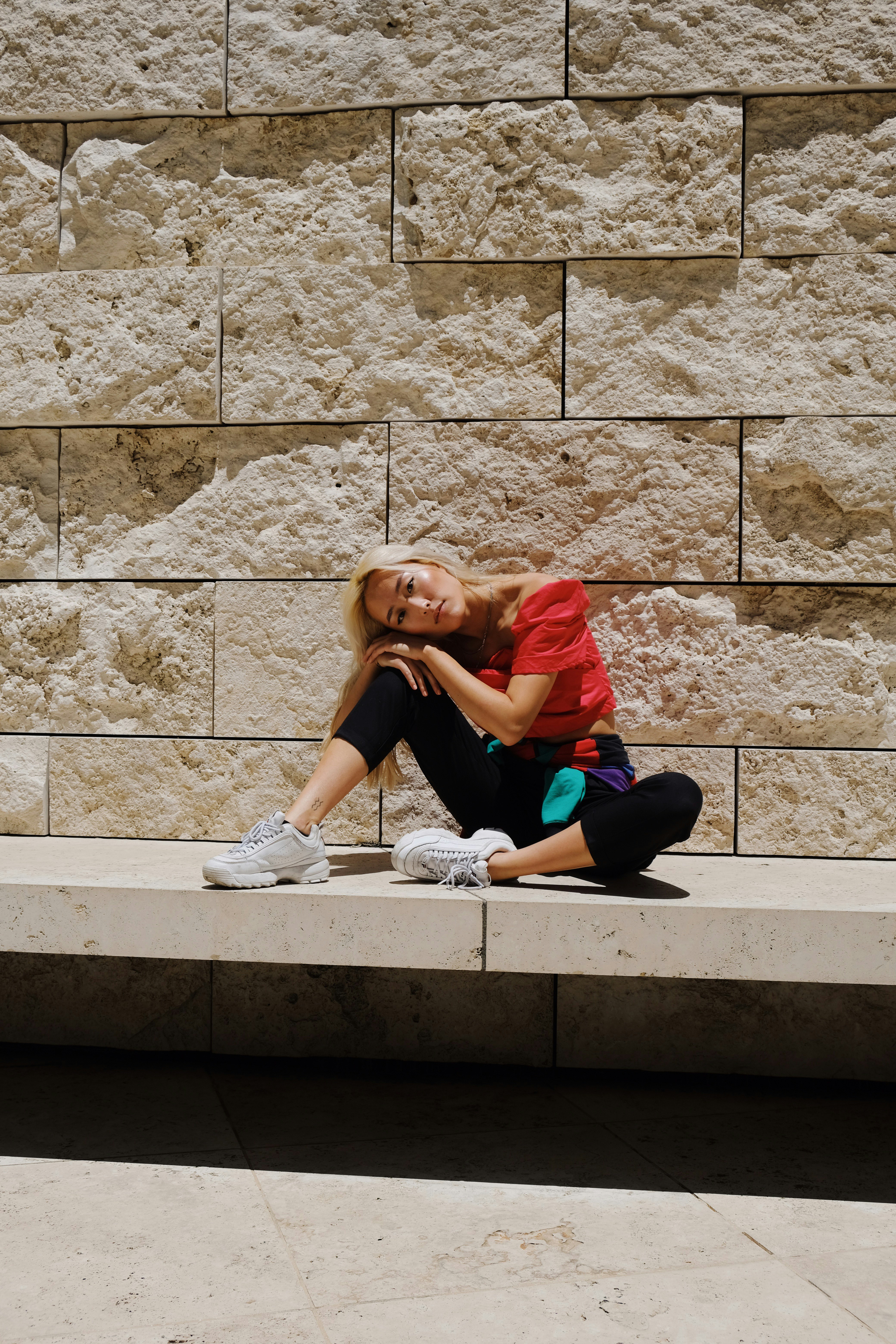 woman in red shirt and blue pants sitting on concrete stairs